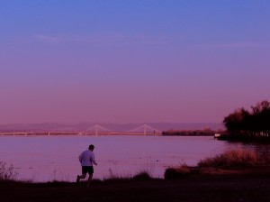 Man running with a bridge in the background